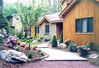 Beautifully redesigned front yard with layered plantings, stone edging, and fresh mulch